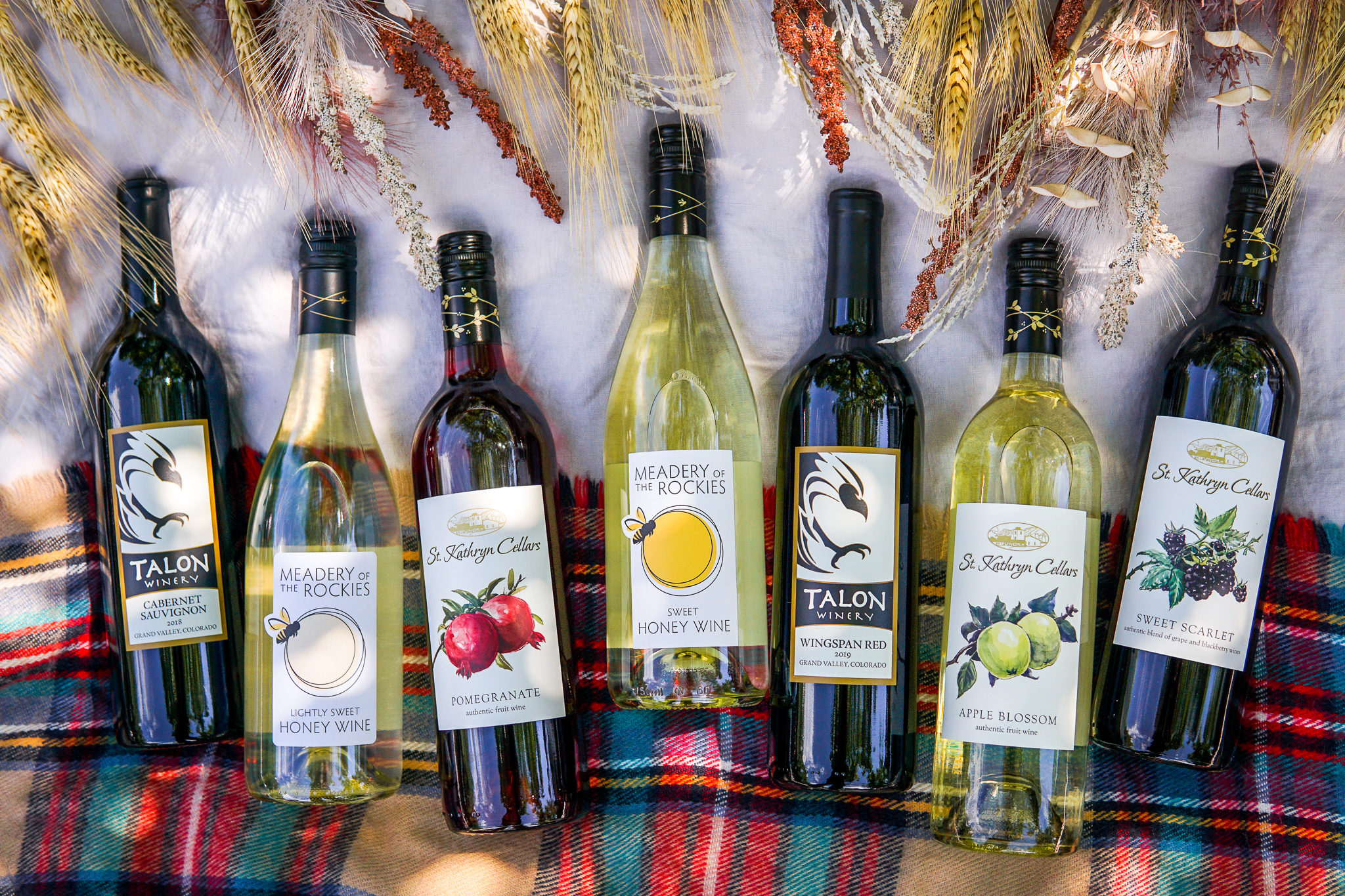 Several bottles of wine lying on a tartan blanket